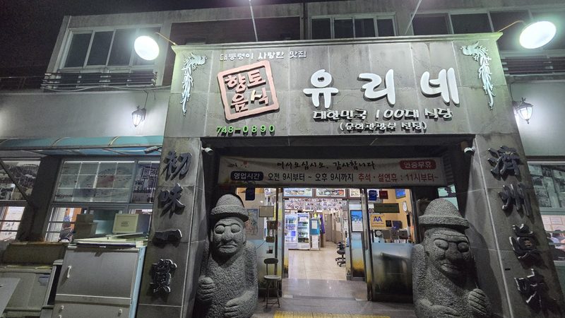 돌하르방 두 기가 지키는 밤의 유리네식당 입구